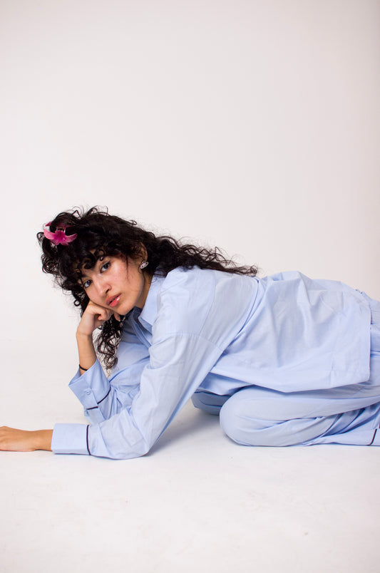 Femme portant un pyjama oversize en coton, assise sur un canapé avec un livre.
Pyjama en coton bleu porté par une femme, ambiance cosy et relaxante.
Look loungewear chic : ensemble en coton naturel, parfait pour une soirée cocooning.